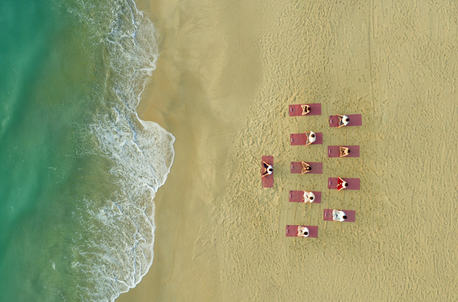 Aerial view of a Hồi Retreat yoga group on the beach beside the ocean